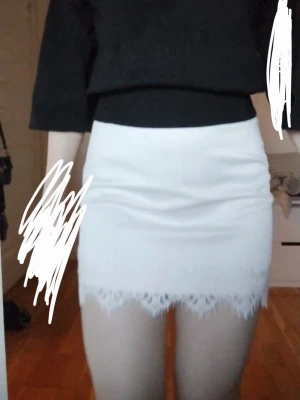 Vit kortkjol med spets från Zara - Supersnygg vit kortkjol från Zara med spetsdetaljer längst ner. Kjolen har en tight passform och är perfekt för dig som vill ha en stilren men ändå söt look. Tillverkad i ett mjukt material likt läder med strecjiga shorts under. :)