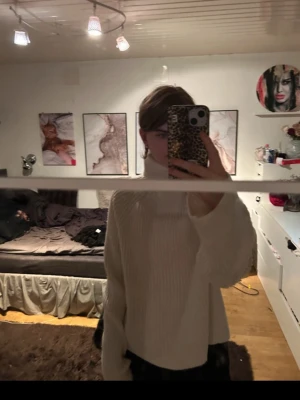 Vit ribbstickad polotröja - Säljer en oversized vit ribbstickad polotröja med hög krage och långa ärmar. Tröjan har en avslappnad passform och är perfekt för kalla dagar. Enkel och stilren design som passar till det mesta. ”Den är köpt begagnat”