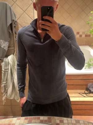 Mörkblå merinoull halvzip - Snygg mörkblå långärmad tröja med halvzip ifrån dressman. Tröjan har ribbade muddar vid ärmslut och nederkant, vilket ger en schysst passform. Perfekt för dig som gillar en stilren och enkel look.