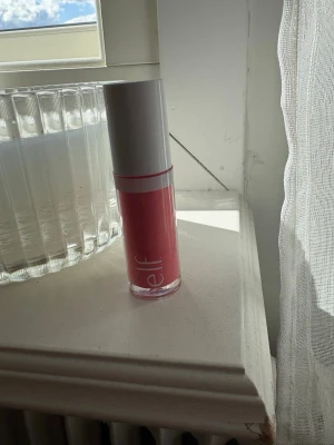 Rosa blush från e.l.f. - Säljer ett snyggt rosa liquid blush från e.l.f. med vit lock och genomskinlig plastförpackning. Applikatorn är mjuk och gör det enkelt att få ett jämnt resultat. Perfekt för dig som vill ha rosa fina kinder. Färgen:punkt promise