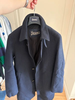 Mörkblå ullrock från Herno - Stilren mörkblå ullrock från Herno med klassisk krage, knäppning framtill och bälte i midjan. Storlek 48 vilket motsvarar en M. Nypris runt 1100 euro. Självklart äkta. Välkomnar seriösa prisförlsag ☺️