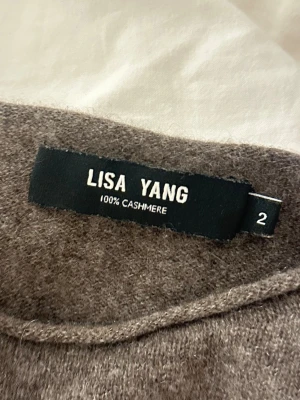 Brun cashmeretröja från Lisa Yang - Mjuk och lyxig brun stickad tröja från Lisa Yang i 100% cashmere. Tröjan har rund halsringning och korta ärmar, perfekt för en avslappnad men ändå stilren look. Nypris 2500kr!