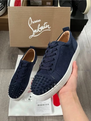 Marinblå sneakers med nitar Louboutin - Snygga marinblå sneakers från Christian Louboutin med tygöverdel och matchande snörning. Skorna har använts ett fåtal par ggr skickar nya bilder om ni är intresserade 