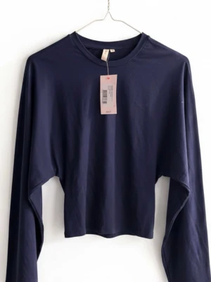 Mörkblå långärmad topp från Nelly - (OANVÄND,PRISLAPP KVAR) En stilren mörkblå långärmad topp från Nelly med rund halsringning. Toppen har en enkel och clean design i mjukt material, perfekt att matcha med jeans eller kjol. Passformen är normal och tyget känns lätt och bekvämt.