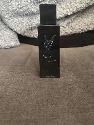 YSL Myself Eau de parfum  - Säljer en elegant Eau de Parfum från Yves Saint Laurent i en stilren, svart rektangulär glasflaska med YSL-loggan i relief på framsidan. Flaskan har sprayfunktion och ger ett lyxigt intryck, perfekt för dig som gillar exklusiva dofter. Inte använd enbart några få sprays då lukten inte fall mig i smaken men passar perfekt för dig som gillar söta dofter nu till hösten.