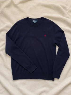 Mörkblå tröja från Polo Ralph Lauren - Polo Ralph Lauren stickad tröja 🐎  * Marinblå * Polo by Ralph Lauren * Röd broderad Polo-logo på bröstet * Storlek XL (18–20) * Klassisk rund hals * Mjuk och stilren modell * Fint skick, se bilder för skick och detaljer kan sänka pris i snabb handling. kan sänka till 199 om det behövs
