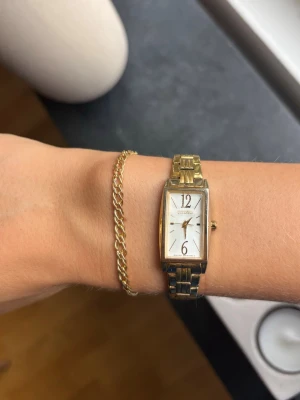 Citizen klocka  - Klocka från Citizen i modell EX0302-51A. Kommer i original-ask. Klockan är i Guldpläterat rostfritt stål. Den är repig i glaset och pläteringen har släppt och gjort den mer silvrig på vissa ställen (se bilder), därav det låga priset. Fortfarande fint helhetsintryck. Kortad för att passa min arm, men avtagna länkbitar medkommer om man behöver förstora den. Nyligen bytt batteri.
