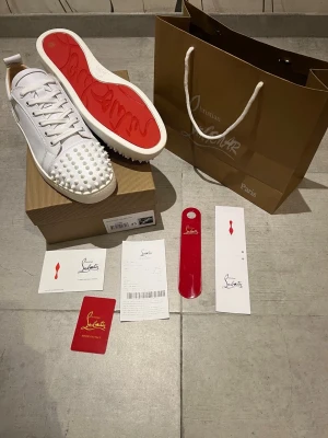 Louboutin skor vit - Hejsan! Jag ger nu mig av med ett par Christian Louboutin skor med spikar. Skorna är i toppskick med inga defekter eller fläckar. Jag har fått de i julklapp men de passar tyvärr inte. De är äkta och köpt i deras butik kvittot finns i annonsen. Nästan allt tillbehör i bilderna ingår. Hör av dig vid frågor och extra bilder! ☺️