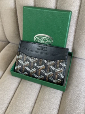 Svart och brun korthållare - Snygg korthållare i svart. Tillverkad i läder och canvas med flera kortfack på både fram- och baksidan. Perfekt för dig som vill ha en stilren och exklusiv accessoar.