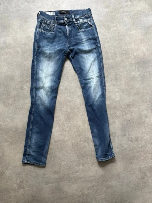 Replay jeans - Snygga blå slim fit jeans med ljusa slitningar på låren och knäna. Klassisk femficksmodell med kontrastsömmar och normalhög midja. Jeansen har en modern tvättad look och raka ben. Perfekta för en avslappnad stil.