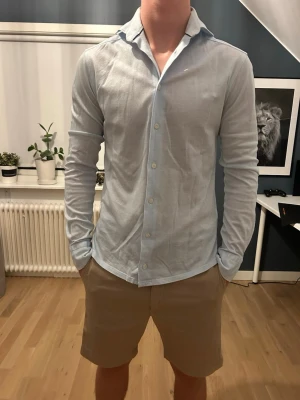 Ljusblå skjorta från Eton - Säljer en stilren ljusblå skjorta från Eton med klassisk krage och vita knappar. Skjortan är långärmad och tillverkad i mjuk bomull, perfekt för en clean och fräsch look. Passar dig som gillar enkel men snygg stil.