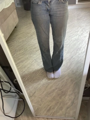 Ljusblå raka jeans med hög midja - Säljer ett par ljusblå jeans med rak passform och låg midja. Jeansen har klassiska fem fickor och är tillverkade i denim. Perfekta för en avslappnad och trendig look.