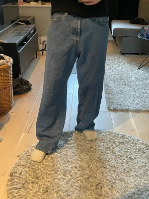 Blåa raka jeans med loose fit - Säljer ett par klassiska blå jeans med rak passform och loose fit. Jeansen har fem fickor, normal midja och stängs med dragkedja och knapp. Perfekta för en avslappnad och trendig stil. Materialet är denim i bomull. Storlek 32/32