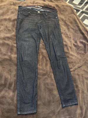 Mörkblå slim jeans med klassisk look - Snygga mörkblå jeans i slim fit med fem fickor och klassisk knappgylf. Jeansen har en enkel och stilren design utan slitningar eller dekorationer, perfekta till vardags. Tillverkade i bomull med en skön passform.