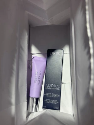 Dior Addict Lip Glow Butter läppbalsam #102 Glazed Lavender - Säljer ett Dior Addict Lip Glow Butter läppbalsam i en snygg lila tub med silverfärgat lock. Ger återfuktade och mjuka läppar med en lyxig känsla. Förpackningen är elegant och modern, perfekt att ha i väskan för snabba touch-ups.