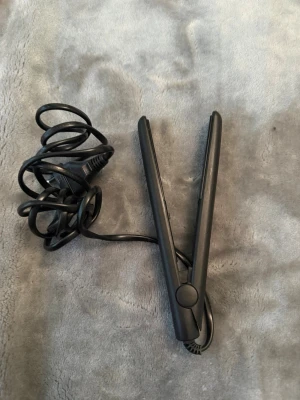 Svart plattång från Beautine - Säljer en svart plattång från Beautine med slimmad design och sladd. Perfekt för att styla håret snabbt och enkelt. Plattången är tillverkad i plast och metall och har en smidig form som gör den lätt att använda.