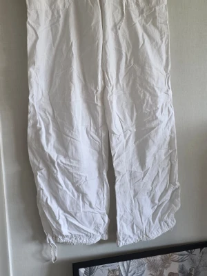 Vita linnebyxor från Vero Moda - Säljer ett par vita linnebyxor från Vero Moda i storlek 38. Byxorna har dragsko vid benslut, knapp och gylf framtill samt en avslappnad passform. Perfekta för en chill och luftig stil under varma dagar.