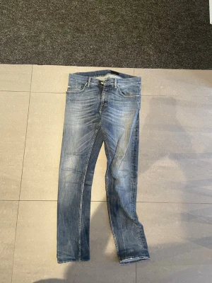 Tiger of Sweden jeans - Säljer ett par blå slim fit jeans med snygga slitningar och tvättade detaljer. Klassisk femficksmodell med bälteshällor och knappgylf. Jeansen har en modern passform och är perfekta till en avslappnad stil.