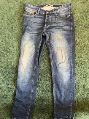 Blå tvättade jeans från The Blue Uniform  - Snygga blå jeans  med klassiska fem fickor och ljus tvätt på låren. Jeansen har normal midja och är tillverkade i denim med stretch för extra komfort. Perfekta för en avslappnad och trendig look.