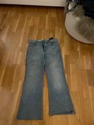 Blåa bootcut jeans från ZARA - Säljer ett par ljusblå bootcut jeans från ZARA med råa, fransiga benslut. Jeansen hög midja och är klippta där nere. Passar för dig som är 159 och under! 