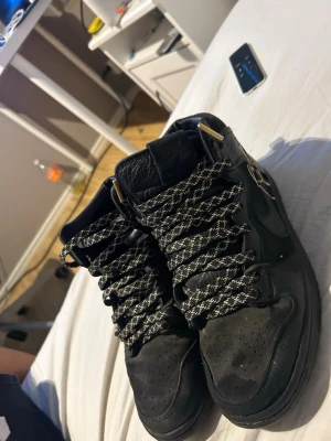 Svarta höga sneakers med mönstrade snören - Pris kan diskuteras. Säljer ett par svarta höga sneakers med svart och vitt mönstrade snören och gulddetaljer på snörändarna. Skorna har en klassisk siluett med perforerad tå och vadderad plös. Materialet ser ut att vara en mix av mocka och läder.