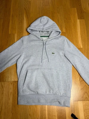 Lacoste hoodie - Säljer denna Lacoste hoodie som ni ser så är den lite smutsig vid insidan av kragen men det är inget som syns när man har på sig den.