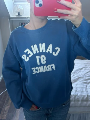 Blå sweatshirt med Cannes-tryck - Säljer denna blåa sweatshirt från HM i storlek M. Väldigt bra skick och finns inte kvar på hemsidan.