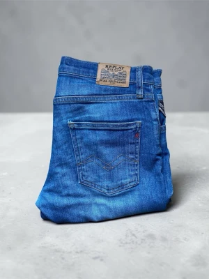 Blå jeans från Replay - Säljer ett par klassiska blå jeans från Replay med snygg tvätt och femficksmodell. Jeansen har normal midja, raka ben och detaljerade sömmar på bakfickan. Tillverkade i mjukt denimtyg som ger en skön passform.