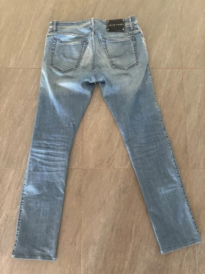 Ljusblå jeans från Jacob Cohën - Snygga ljusblå jeans från Jacob Cohën med raka ben och klassisk femficksmodell. Jeansen har kontrastsömmar och en svart patch med logga bak i midjan. Tillverkade i mjukt denimtyg som ger en avslappnad look. Skriv gärna vid frågor och funderingar, priset är ej hugget i sten 😊
