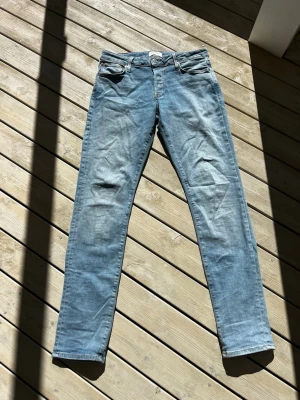Ljusblå raka jeans från Jack & Jones - Säljer ett par ljusblå jeans från Jack & Jones med raka ben.  Stängs med enbart knappar. Endast ett liten svart prick på baksidan av benet under till, som man inte tänker på när dom sitter på. Storlek 33/34. Nypris 1000kr. Pris kan diskuteras! 