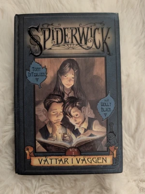 Spiderwick: Vättar i väggen bok 1 - Spiderwick: Vättar i väggen är en hårdinbunden fantasybok med mörkblått omslag och illustration av tre barn som läser. Skriven av Tony DiTerlizzi och Holly Black. Perfekt för dig som gillar magiska äventyr och spännande berättelser.
