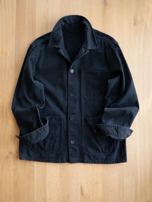Svart overshirt i bomull - Stilren svart overshirt med tre stora utanpåfickor och knäppning framtill. Tillverkad i kraftig bomull med klassisk krage och raka ärmar. Perfekt lager-på-lager-plagg för en avslappnad look. Notera skadan på armen. 