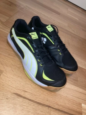 Puma Ballesta Skor - Säljer ett par nya svarta Puma skor med gula detaljer. Skorna har svarta snören med ljusbrun/gul sula. Skorna är använda 2-3 ggr men det finns inga tydliga tecken på användning, så dom funkar som helt nya. Perfekta för sport och träning, men funkar också som vardagliga skor.
