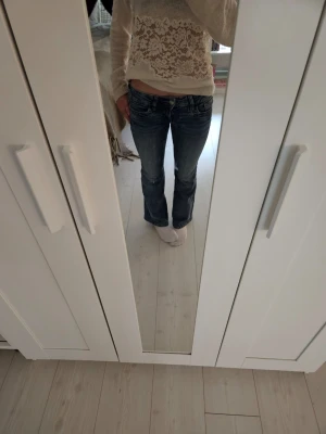 Blå bootcut jeans  - Säljer ett par blå bootcut jeans med låg midja. Jeansen har snygga slitningar och kontrastsömmar för en cool look. Säljer för att de är för små. Knappt använda och inga deffekter 