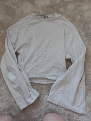 Vit långärmad figursydd topp i bomull - En enkel och stilren vit långärmad topp i mjuk bomull. Modellen har rund halsringning och en något croppad passform. Perfekt att matcha med jeans eller kjol för en clean look.