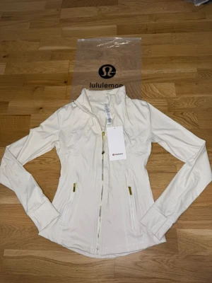 Vit Nulu define jacket Lululemon Stl.4 - Den lite mindre och smalare versionen av lululemons define jacket I Stl 4 som motsvarar runt S eller en riktigt tight M. Jag hade rekommenderat S för bäst passform. Den är helt oanvänd och ren!💞💞
