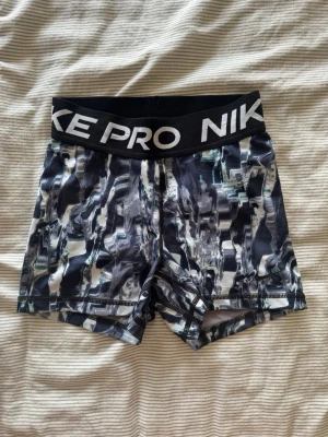 Nike Pro svarta mönstrade träningsshorts - Nike Pro träningsshorts med svartvit och blå abstrakt mönstring. Säljer för dom har blivit för små