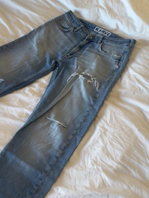 Ljus blå kavre jeans med slitningar. - Mått:  Midja 41cm Lår 25cm Knä 22cm Benöppning 18cm Längd 106cm Några undringar är det bara att fråga.