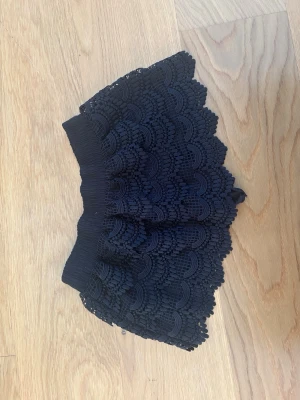 Svarta korta shorts med spetsvolang - Supersnygga korta shorts med bred resår i midjan och detaljerad spetsvolang. Perfekta för sommaren 