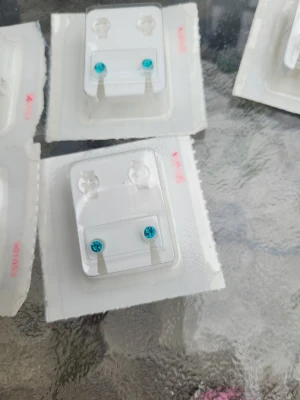 Små turkosa örhängen i plast - Säljer ett par små örhängen med turkosa stenar. Örhängena är runda och sitter på genomskinlig plastbricka. Perfekta för dig som gillar diskreta men färgglada accessoarer.