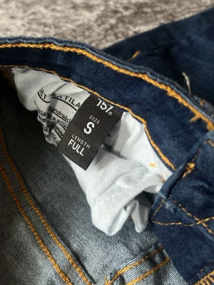 Mörkblå jeans med full längd - Snygga mörkblå jeans i full längd med klassisk femficksmodell och kontrastsömmar. Jeansen har en rak passform och är tillverkade i ett mjukt denimtyg som sitter skönt. Perfekta till vardagslooken och lätta att matcha med olika stilar.