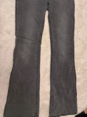 Gråa bootcut jeans - Säljer ett par gråa bootcut jeans med klassisk femficksmodell. Jeansen har en lätt utsvängd passform nedtill och är tillverkade i ett mjukt denimtyg. Perfekta för dig som gillar en avslappnad men ändå trendig look. Aldrig använt och kostar helt nytt 349