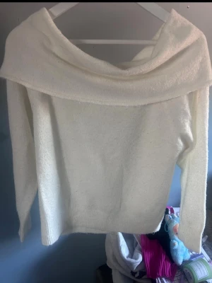 Vit off shoulder stickad tröja - Säljer en vit stickad tröja med bred off shoulder-krage. Tröjan har långa ärmar och är gjord i ett mjukt, mysigt material som passar perfekt till kyligare dagar. Enkel och stilren design som är lätt att matcha med olika outfits.