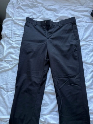 Svarta kostymbyxor från H&M Slim Fit - Snygga svarta kostymbyxor från H&M i modellen Slim Fit. Byxorna har klassisk design med hällor för bälte och raka ben. Perfekta för en stilren look och tillverkade i ett mjukt tyg som ger en bekväm känsla.