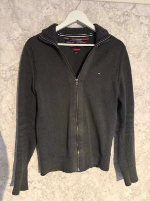 Mörkgrå ziptröja Tommy Hilfiger - Tjena, säljer nu en Mörkgrå stickad ziptröja från Tommy Hilfiger med liten logga på bröstet. Den är i mycket bra skick och inga synliga defekter, den är i premium cotton och har en mycket bra passform. Storlek S, har du någon fundering är de bara att skriva, ge gärna prisförslag!!