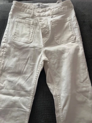 Högmidjade vita jeans - Säljer ett par vita jeans med utsvängda jeans. Jeansen har hög midja.