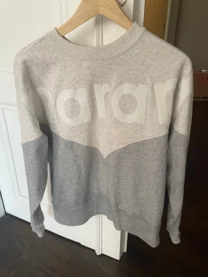 Grå sweatshirt från Isabel Marant Etoile - ny, aldrig använd  - Säljer en stilren grå sweatshirt från Marant Etoile i storlek 36. Aldrig använd, bara tvättad! Tröjan har klassisk rund halsringning och ribbade muddar vid ärmslut och nederkant. Perfekt för en avslappnad och trendig look. Modell Houston. Nypris var 3700.