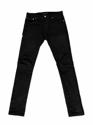 Svarta slim jeans från Nudie Jeans - Snygga svarta slim jeans från Nudie Jeans med klassisk femficksmodell och knappgylf. Jeansen har en smal passform och är tillverkade i ett mjukt denimtyg som sitter tajt längs benen. Perfekta för en clean och stilren look.