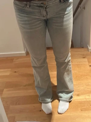 Ljusblå bootcut jeans - Säljer ett par ljusblå bootcut jeans med klassisk femficksdesign och hög midja. Jeansen har en lätt tvättad look och vida ben från knät och ner. Passar perfekt till en avslappnad stil och är tillverkade i ett mjukt denimtyg.