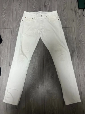 Vita Polo Ralph Lauren jeans - Säljer ett par vita Polo jeans med rak passform och klassisk femficksdesign. Jeansen har normal midja och stängs med knapp och dragkedja. Perfekta för en clean och stilren look.